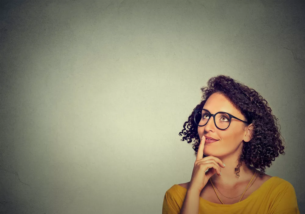 woman looking up and thinking on grey wall background